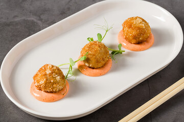 Three roasted chicken meatballs served with spicy dipping sauce and greens