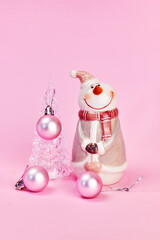 a card on which a beautiful transparent Christmas tree is decorated with pink balls and a smiling snowman next to it, pink background, vertical, creative focus