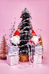 funny Christmas picture in which two gnomes, stand on gift boxes and decorate the tree with a...