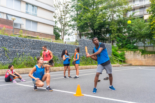 Baseball player hitting ball during friendly match in urban area - Powered by Adobe