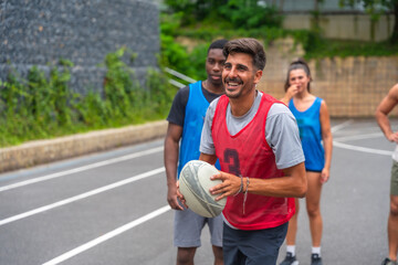 Rugby player smiling and holding ball during training with teammates