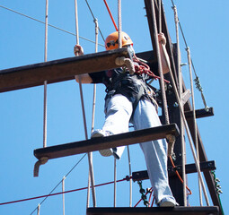 a girl in a special costume is preparing to climb ropes at high altitude