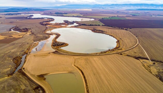 Aerial oxbow lake remnant arcs on floodplain muted earth tones wallpaper representing river landscape history suitable for natural geography design