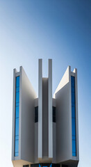 Modern architectural building with blue windows reaching towards a clear blue sky.