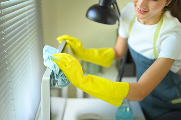 Woman in apron and protective gloves disinfecting computer equipment with care
