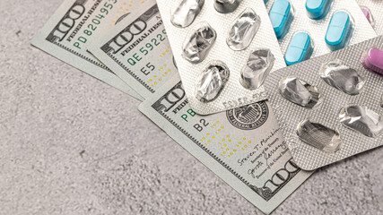 Dollar bill and a set of medicine pills. Rising costs of medical care. Reliefs for buying medicine.Pills in capsules scattered on US dollars currency.Concept of health care in USA.