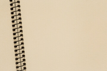 close up of empty beige page of sketchbook with spiral binder