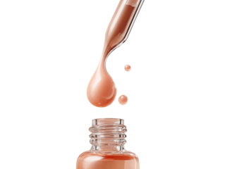 A drop of light peach-toned serum falls from a glass dropper bottle