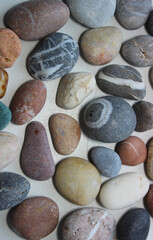 Vertical photo of multicolored pebbles and gray sea stones with quartz patterns inside
