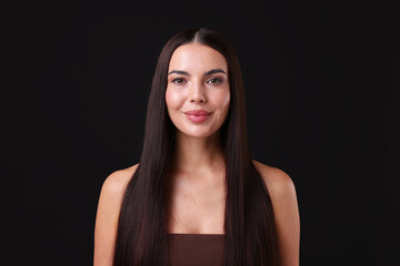 Woman with beautiful smooth hair after lamination procedure on black background
