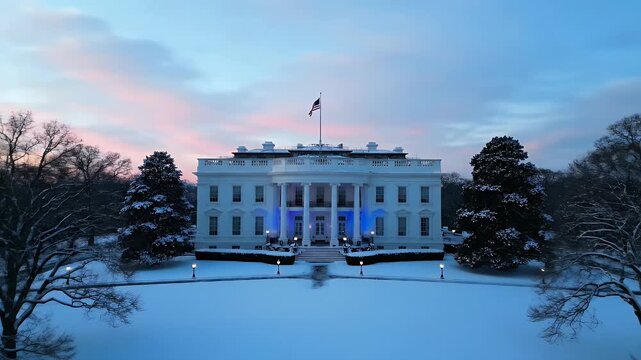 Snow-covered White House at dusk, illuminated with blue lights.