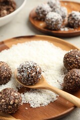 Making tasty chocolate candies with nuts and coconut flakes at light table, closeup