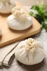Uncooked khinkalis (dumplings) and cilantro on wooden table, closeup