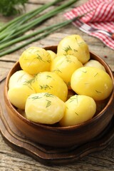 Tasty young boiled potatoes with dill served on wooden table, closeup