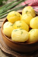 Tasty young boiled potatoes with dill served on wooden table, closeup