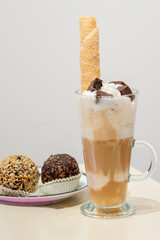 A tall glass of latte macchiato sits next to small cookies. The coffee, layered with milk and espresso, creates an aesthetically pleasing look. This photo is perfect for topics related to coffee