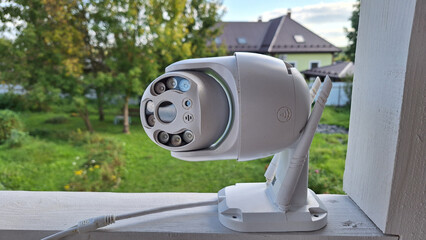 Outdoor security camera on porch with green garden view in background