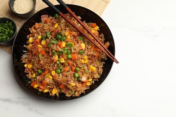 Tasty fried rice and chopsticks on white marble table, flat lay. Space for text
