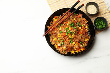 Tasty fried rice and chopsticks on white marble table, flat lay. Space for text