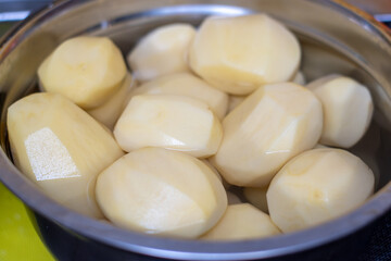 raw peeled potatoes in a stainless steel bowl, organic peeled potatoes ready for cooking