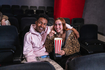 Happy couple sharing laughter and popcorn while enjoying a movie at the cinema, creating joyful memories together in the cozy auditorium