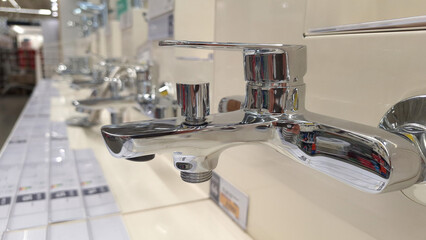 Chrome bathroom faucet display in store aisle with modern fixtures and design options