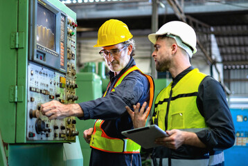 Two men in safety gear are working on machine