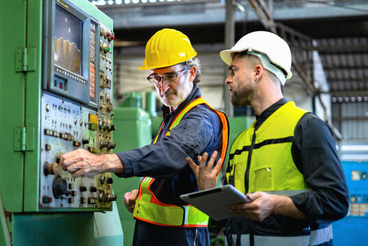 Two men in safety gear are working on  machine - Powered by Adobe