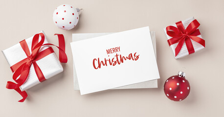 Christmas holiday greeting card with gift box and xmas ball decoration on light beige background