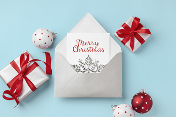 Merry christmas holiday greeting card with gift box with red bow ribbon and xmas ball decor on blue...