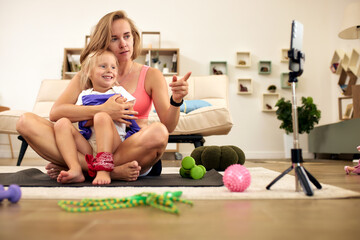 Mother and daughter enjoying video tutorial together on fitness mat at home