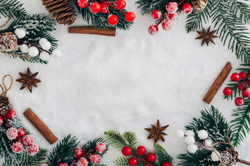 Winter scene of green tree branches with red berries on snowy background. Christmas and New Year concept. Creative festive holiday backdrop. Border arrangement. Top view banner. Copy space.