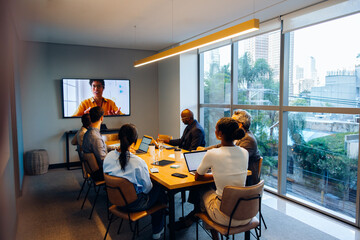 Group of professionals in a meeting with a video call participant