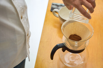 ドリッパーに中細挽きの豆の粉を入れる男性。ペーパードリップでコーヒーを淹れる工程の連続写真。