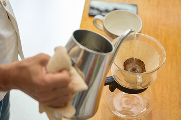  1回目の蒸らしの湯を注ぐ男性。ペーパードリップでコーヒーを淹れる工程の連続写真。
