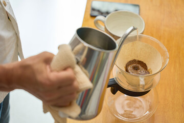  1回目の蒸らしの湯を注ぐ男性。ペーパードリップでコーヒーを淹れる工程の連続写真。
