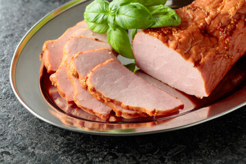 Delicious smoked ham with basil on a metal tray.
