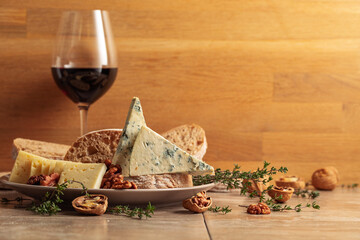 Cheese, bread, red wine, and walnuts on a kitchen table.