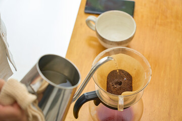 2回目3回目の抽出用の湯を注ぐ男性。ペーパードリップでコーヒーを淹れる工程の連続写真。