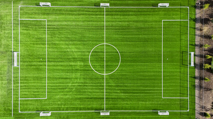 A soccer field with a white goal and a white circle in the middle. The field is green and well maintained