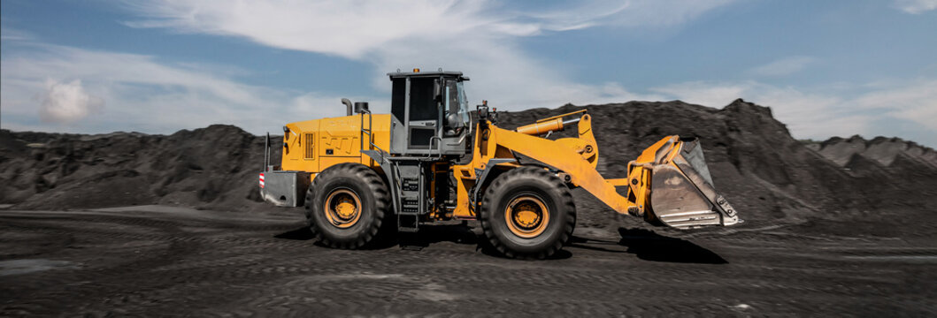 Loading of an loader into railway wagons. Excavator loading coal into wagons. Loading of coal truck using excavator. Shipment coal for transportation by rail