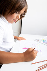 Young caucasian female child drawing with colorful pencils at home art table