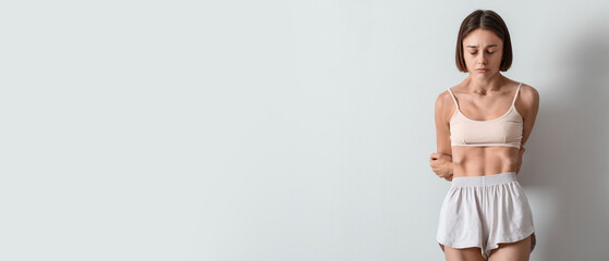Young skinny woman on light background. Anorexia concept