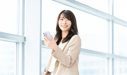 スマートフォンを持つ笑顔の女性・ビジネスウーマン