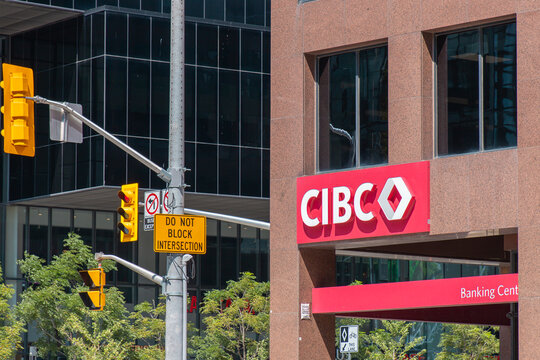 Toronto, ON, CANADA - Aug 8 2024 : CIBC bank branch on a city street corner with traffic signs, modern buildings, and urban intersection in bright daylight.