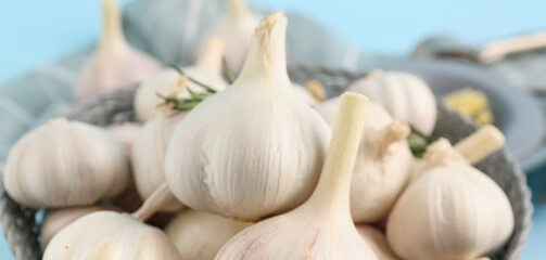 Bowl with fresh garlics on blue background, closeup