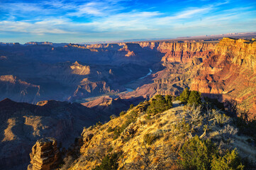 Grand Canyon at sunset viewed from Desert View Watchtower, showcasing vibrant canyon walls and the Colorado River winding through the landscape.
