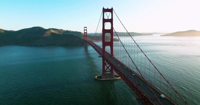 Aerial view of the iconic Golden Gate Bridge with cars traversing its length, connecting distant lands across the serene blue waters, San Francisco, California, United States.