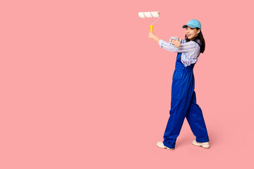 Naklejka premium Female Asian painter with roller showing thumb-up gesture on pink background