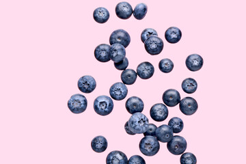 Flying fresh blueberries on pink background
